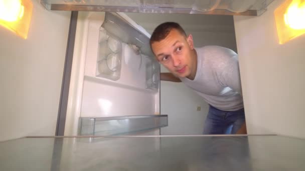 El hombre abre el refrigerador, olfateando y tapándose la nariz — Vídeos de Stock