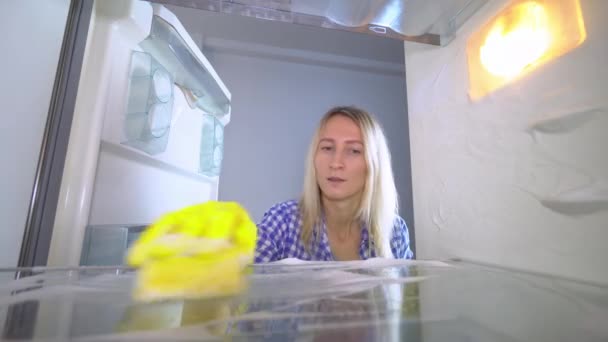 Een ontevreden en geïrriteerde vrouw wast en reinigt zich in de koelkast — Stockvideo