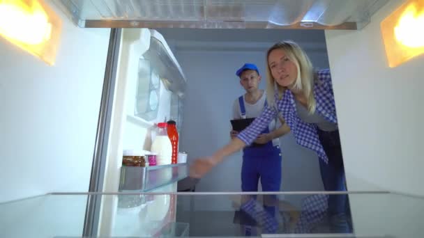 Naprawiacz lodówki otwiera drzwi i listę prac — Wideo stockowe