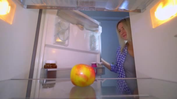 La femme ouvre le réfrigérateur, dans lequel il n'y a qu'une pomme. Elle est bouleversée.. — Video