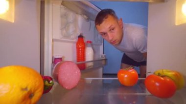 İç çamaşırlı adam buzdolabını açıyor, esniyor, ağzını kapatıyor, bir sosis alıyor.