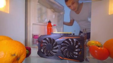 Adam buzdolabını açıyor ve soğutmak için aşırı ısınmış video kartını rafa koyuyor..