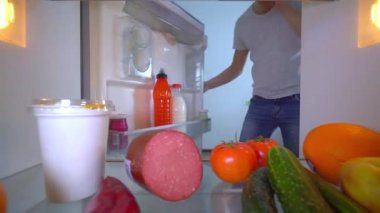 Adam cep telefonuyla konuşuyor, buzdolabının kapısını açıyor ve sütü çıkarıyor.