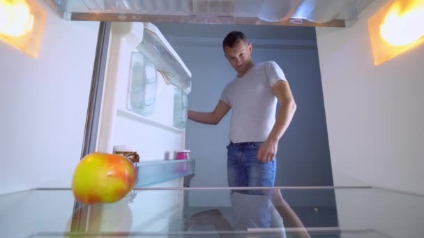 Tipo abre el refrigerador donde está vacío y apunta a su vientre con grasa. — Vídeos de Stock