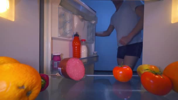 Mężczyzna w bieliźnie otwiera lodówkę, tańczy, bierze pomidora, widok od wewnątrz. — Wideo stockowe