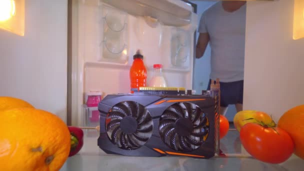 Homem abre geladeira e coloca placa de vídeo superaquecida na prateleira para resfriamento. — Vídeo de Stock