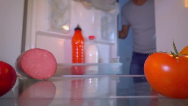 Чоловік відкриває холодильник і кладе перегріту відеокарту на полицю для охолодження . — стокове відео