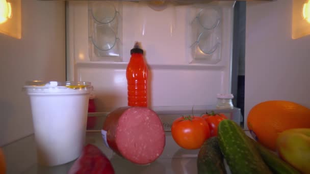 Человек открывает холодильник и кладет бутылку молока на полку. — стоковое видео