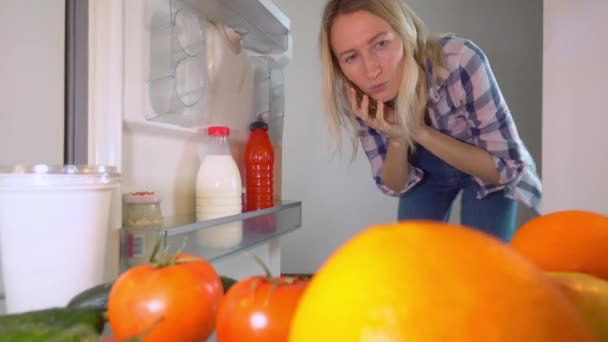 Vrouw is praten op een mobiele telefoon, opent koelkast deur en haalt melk — Stockvideo