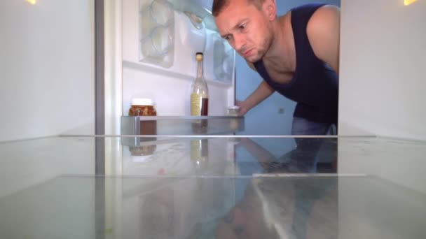 Mann blickt in leeren Kühlschrank und holt Flasche mit Alkohol heraus. Alkoholismus — Stockvideo