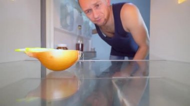 Adam boş bir buzdolabına bakar ve bir şişe alkol çıkarır. Alkolizm