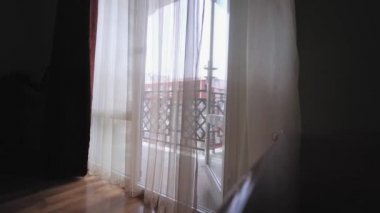 Pencerede şeffaf bir perde, odada rüzgarda hafifçe sallanıyor..