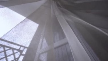 Pencerede şeffaf bir perde, odada rüzgarda hafifçe sallanıyor..