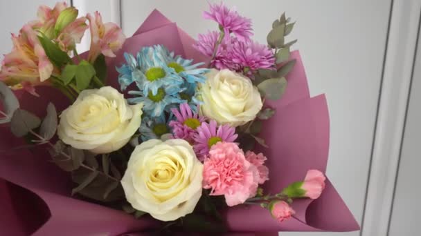 Närbild av en vacker bukett av olika blommor i en ljus rosa paket. — Stockvideo