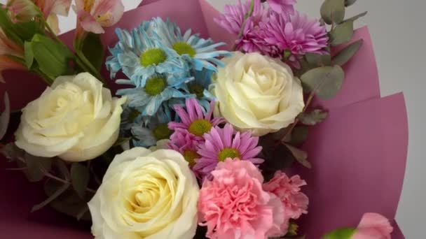 Nahaufnahme eines schönen Straußes aus verschiedenen Blumen in einem leuchtend rosa Paket. — Stockvideo