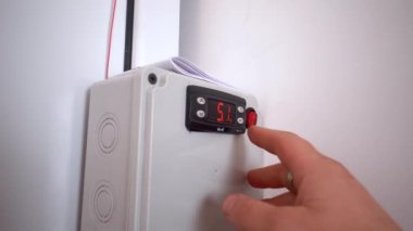 Bir adamın eli buzdolabı kontrol modülünün sıcaklığını ayarlar..