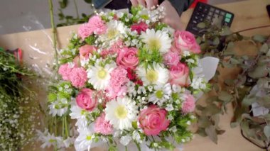 Bir kompozisyon oluşturan genç bir kadın çiçekçinin ellerinin üst görüntüsü