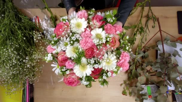 Vista superior de las manos de una florista joven creando una composición — Vídeo de stock