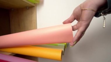 Çiçekçi raftan renkli bir buket çiçek almak için renkli kâğıt alıyor ve kesiyor.