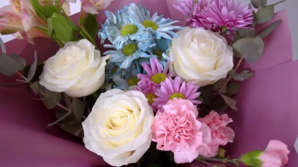 Primer plano de un hermoso ramo de diferentes flores en un paquete de color rosa brillante. — Vídeos de Stock
