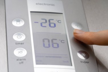 Bir kadının elinin yakın çekimi buzdolabının ısısını düzenler. Modern gri buzdolabı çok şık. Kadının eli sıcaklığı eksi yirmi altı dereceye düşürür.