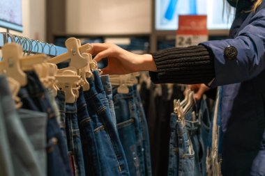 Alışveriş merkezinde kot pantolon seçen kadınların yakın çekimleri. Alışveriş konsepti