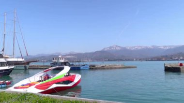 BATUMI, GEORGIA - 13 Nisan 2022: Gürcistan 'ın Batumi limanındaki modern teknelerin yakınında, rıhtım ve turistler arasında panorama. Turistler ve denizciler .