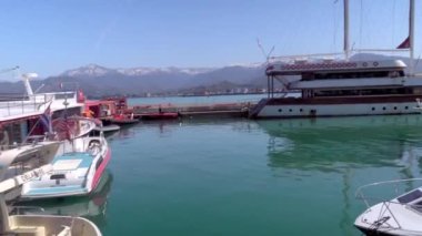 BATUMI, GEORGIA - 13 Nisan 2022: Gürcistan 'ın Batumi limanındaki modern teknelerin yakınında, rıhtım ve turistler arasında panorama. Turistler ve denizciler .