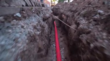 Yeni izole edilmiş internetin eve güvenli bağlantısı, gaz kartı, kırmızı metal banttan yapılmış sistemin inşaatı şehir caddesinde kazılmış çukurda bulunuyor. Üst görüntü, yerdeki dengeleyicide kamera hareketi.