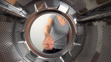chamber is inside drum of washing machine. woman's hand shows fig and an obscene gesture, fuck you. woman puts her hand inside and shows that she is tired of doing laundry and cleaning. wants to rest