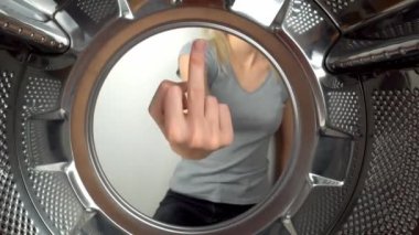 chamber is inside drum of washing machine. woman's hand shows fig and an obscene gesture, fuck you. woman puts her hand inside and shows that she is tired of doing laundry and cleaning. wants to rest