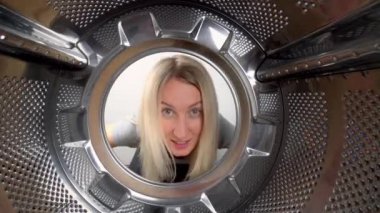 Genç güzel sarışın kafasını çamaşır makinesine sokuyor. Öfkeden bağırıyor, çamaşır yıkamak istemiyor ve sürekli temizlik ve çamaşır yıkamaktan yoruluyor. Davulun içinden, geniş açılı kamera görüntüsü.