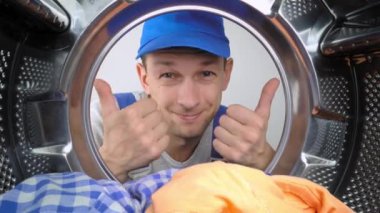 Bir ev aletleri yıkama makinesi remommer yanıtlayıcısı çamaşır makinesinin içine bakar ve parmağını işaret ederek iyi ya da iyi işaret eder. Sınıf. Bir sürü iş yapıldı. Hizmet adamları.
