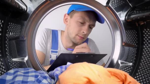 Ung Tvättmaskin Reparatör Tittar Trumma Och Skriver Ner Listan Över — Stockvideo