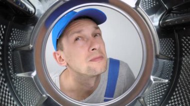 Kokmuş çamaşır makinesi ve çamaşır odası. Usta tamirci çamaşır makinesinin içine bakar, pis kokuyu alır ve burnunu tıkar. Davulun içinden geniş açıyla bak. Koku giderici. Adam.