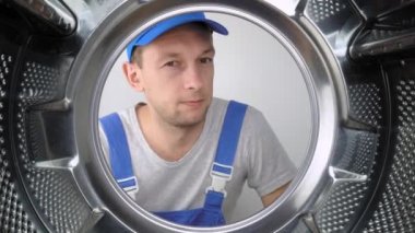 Bir ev aletleri yıkama makinesi remommer yanıtlayıcısı çamaşır makinesinin içine bakar ve parmağını işaret ederek iyi ya da iyi işaret eder. Sınıf. Bir sürü iş yapıldı. Hizmet adamları.