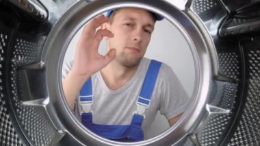 Bir ev aletleri yıkama makinesi remommer yanıtlayıcısı çamaşır makinesinin içine bakar ve parmağını işaret ederek iyi ya da iyi işaret eder. Sınıf. Bir sürü iş yapıldı. Hizmet adamları.