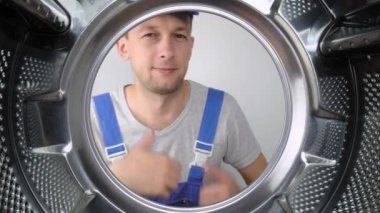 Bir ev aletleri yıkama makinesi remommer yanıtlayıcısı çamaşır makinesinin içine bakar ve parmağını işaret ederek iyi ya da iyi işaret eder. Sınıf. Bir sürü iş yapıldı. Hizmet adamları.