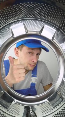 Bir ev aletleri yıkama makinesi remommer yanıtlayıcısı çamaşır makinesinin içine bakar ve parmağını işaret ederek iyi ya da iyi işaret eder. Sınıf. Bir sürü iş yapıldı. Hizmet adamları.