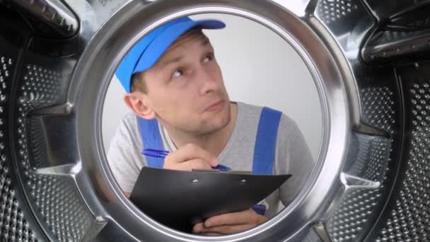 Jonge Wasmachine Reparateur Kijkt Naar Trommel Schrijft Een Lijst Van — Stockvideo