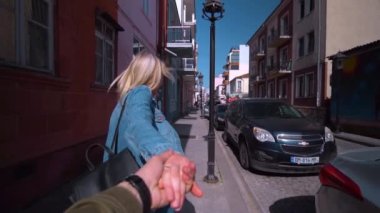 Batumi, Georgia - 12 Nisan 2022: Genç güzel bir kız adama yaklaştı, elini tuttu ve şehirde ağır çekimde koştular. Geniş açıyla vurulan birinci şahıs. Birbirine aşık gezginler. Aşka güven.