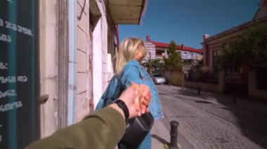 Batumi, Georgia - 12 Nisan 2022: Genç güzel bir kız adama yaklaştı, elini tuttu ve şehirde ağır çekimde koştular. Geniş açıyla vurulan birinci şahıs. Birbirine aşık gezginler. Aşka güven.