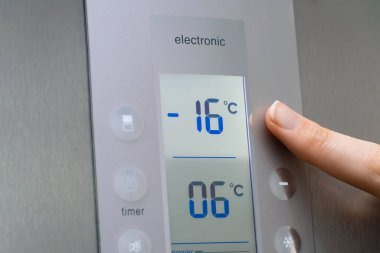 Bir kadının elinin yakın çekimi buzdolabının ısısını düzenler. Modern gri buzdolabı. Kadının eli sıcaklığı eksi on altı dereceye çıkarıyor.