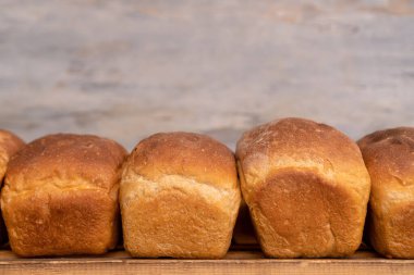 Ahşap raflarda taze pişmiş ekmeğin yakın çekimi, ön manzara. Fırın ürünlerinin üretimi