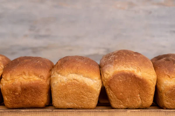 Ahşap raflarda taze pişmiş ekmeğin yakın çekimi, ön manzara. Fırın ürünlerinin üretimi