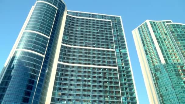 Нижний вид на современные небоскребы в деловом районе против голубого неба — стоковое видео