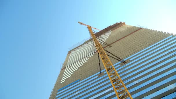 Γερανός πύργος συνδέεται με το πλαίσιο του κτιρίου. Κατασκευή ουρανοξύστη. — Αρχείο Βίντεο