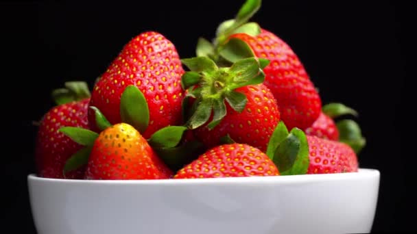 Appetizing strawberries with wilted green leaves lie on white porcelain bowl — Vídeo de Stock