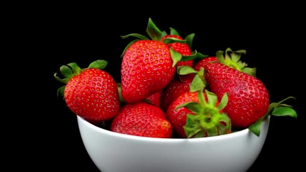 Appetitliche Erdbeeren mit welken grünen Blättern liegen auf weißer Porzellanschale — Stockvideo