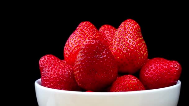 Fresas sin colas se encuentran en un tazón blanco o plato. Rota. — Vídeos de Stock